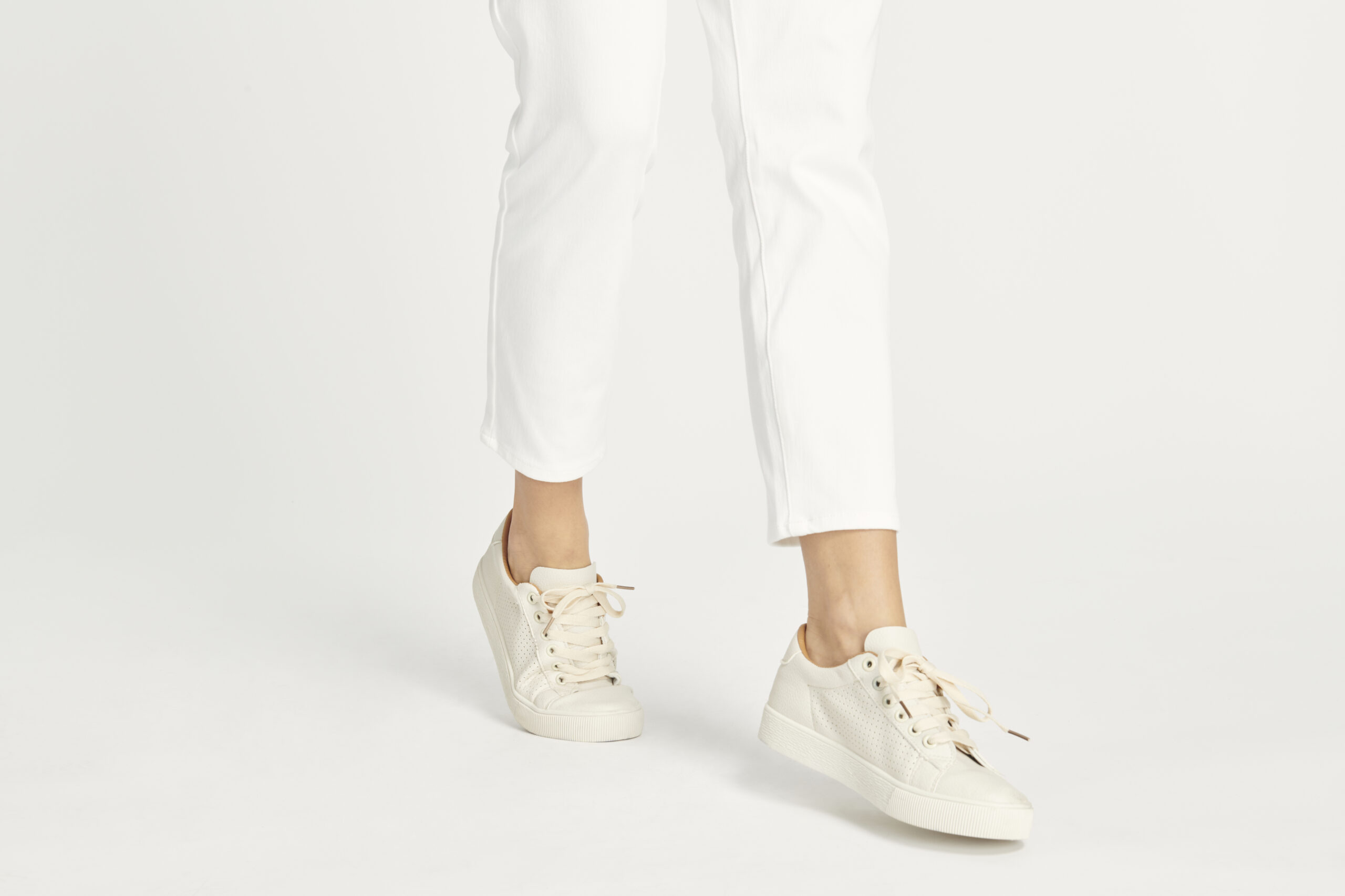 Mulher usando tênis branco com calças longas